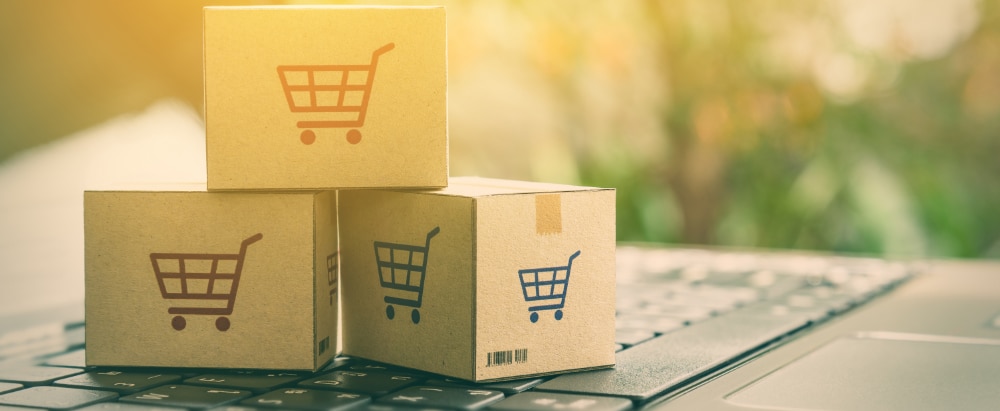 Online shopping / ecommerce and delivery service concept : Paper cartons with a shopping cart or trolley logo on a laptop keyboard, depicts customers order things from retailer sites via the internet.