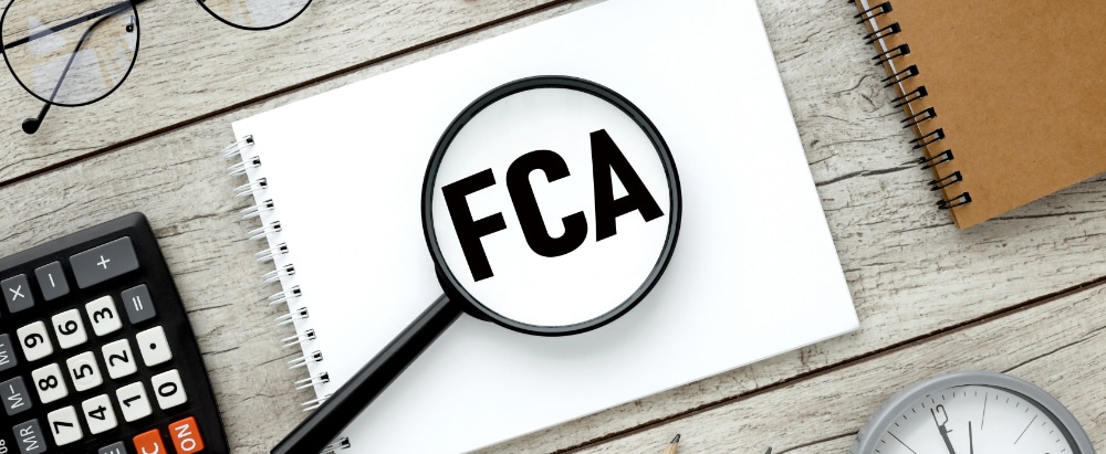 FCA. text on magnifier glass on white background. notepad on the desktop.